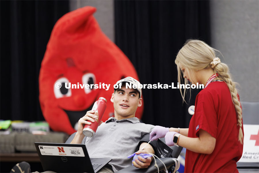 Under the watchful eyes of Buddy the Blood Drop, Caleb Preister, a junior from Lindsay, Nebraska, gives blood during the Homecoming blood drive. Homecoming Week 2023. October 24, 2023. Photo by Craig Chandler / University Communication.