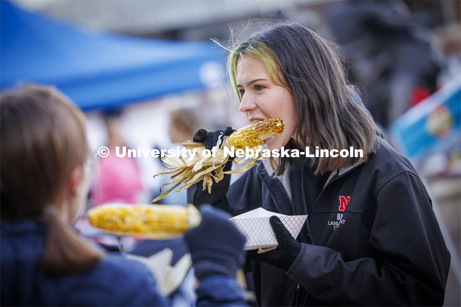 Lani Bohmont digs into an ear of roasted corn at Cornstock. Homecoming parade and Cornstock. October 27, 2023. Photo by Craig Chandler / University Communication.