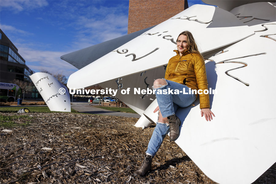 Nonie Mitchell, a senior in secondary education, attends UNL with a scholarship from The Nebraska Promise program. The program covers undergraduate tuition at the University of Nebraska's four campuses (UNK, UNL, UNMC and UNO) and its two-year technical college (NCTA). Mitchell is posing by the Torn Notebook Sculpture on City Campus. November 27, 2023. Photo by Craig Chandler / University Communication and Marketing.