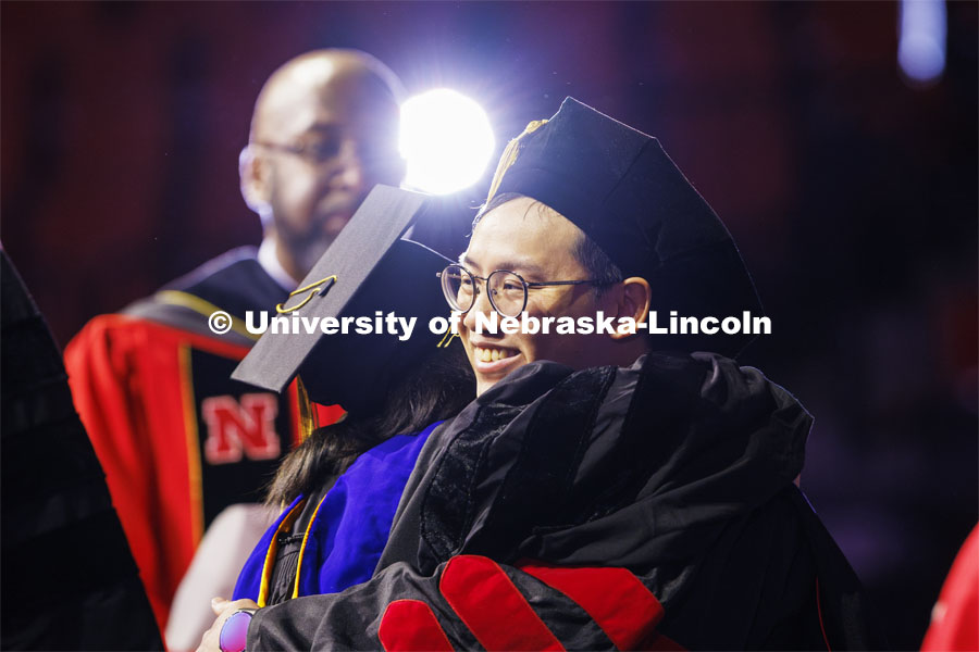 Biquan Zhao hugs one of his advising professors after receiving his doctoral degree in natural resource sciences. Graduate Commencement at Pinnacle Bank Arena. December 15, 2023. Photo by Craig Chandler / University Communication and Marketing.