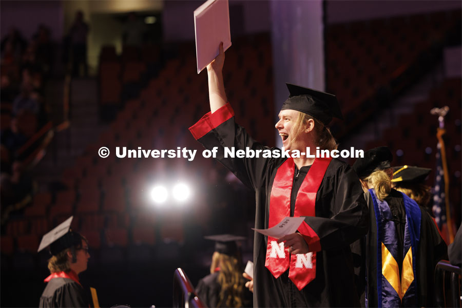Jo Stollar waves to family and friends after receiving the diploma. Winter undergraduate commencement in Pinnacle Bank Arena. December 16, 2023. Photo by Craig Chandler / University Communication and Marketing.