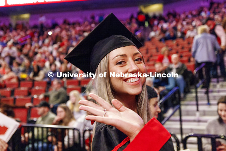 Chloe Schock, CoJMC graduate, waves as she leaves the arena. Winter undergraduate commencement in Pinnacle Bank Arena. December 16, 2023. Photo by Craig Chandler / University Communication and Marketing.