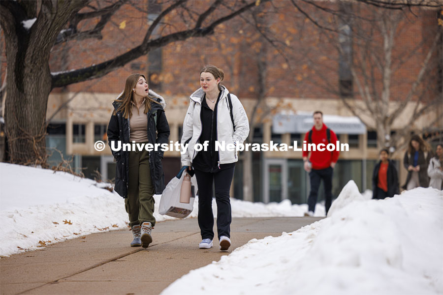 Jayda Feeney, left, and Sara Ehlers walk across campus Tuesday. Snow on city campus. January 23, 2024. Photo by Craig Chandler / University Communication and Marketing.