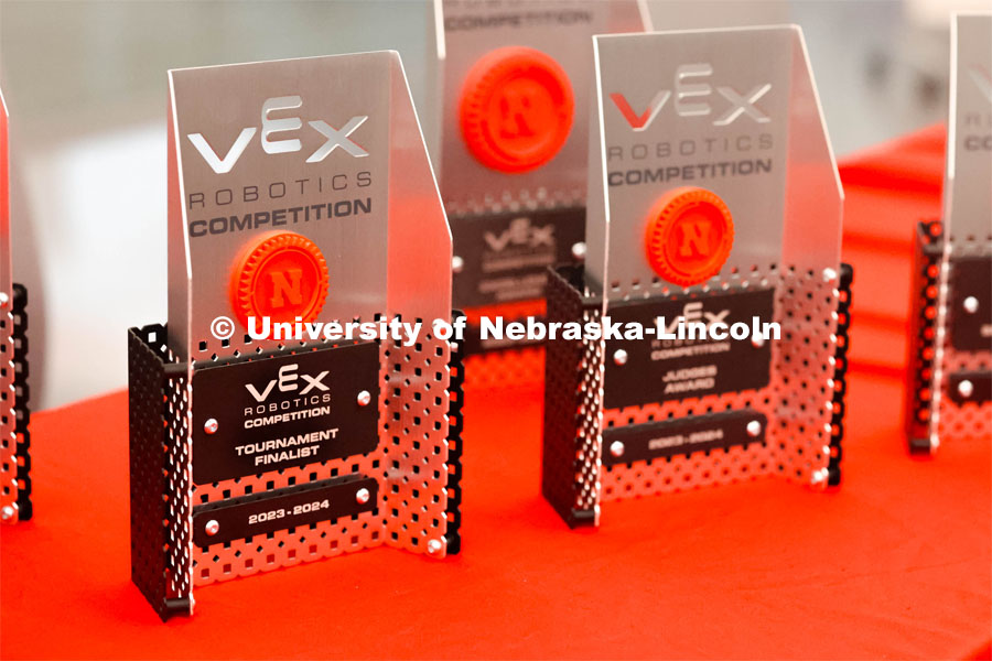 Competition trophies are lined up on a table. 2024 VEX Robotics Outreach Tournament hosted in Kiewit Hall. February 10, 2024. Photo by Taryn Hamill for University Communication and Marketing.