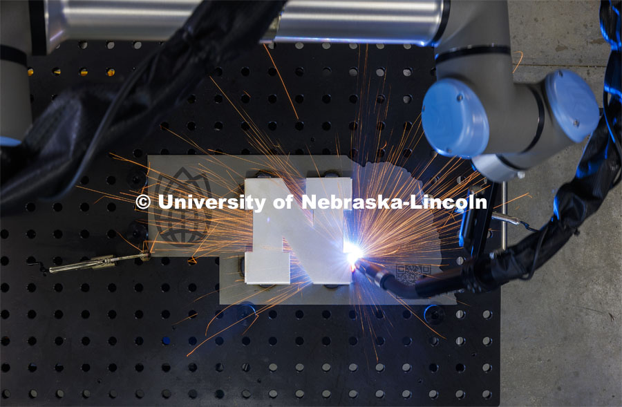 A robotic welder at Nebraska Innovation Studio welds a Nebraska N to a cutout in the shape of Nebraska. March 14, 2024. Photo by Craig Chandler / University Communication and Marketing.