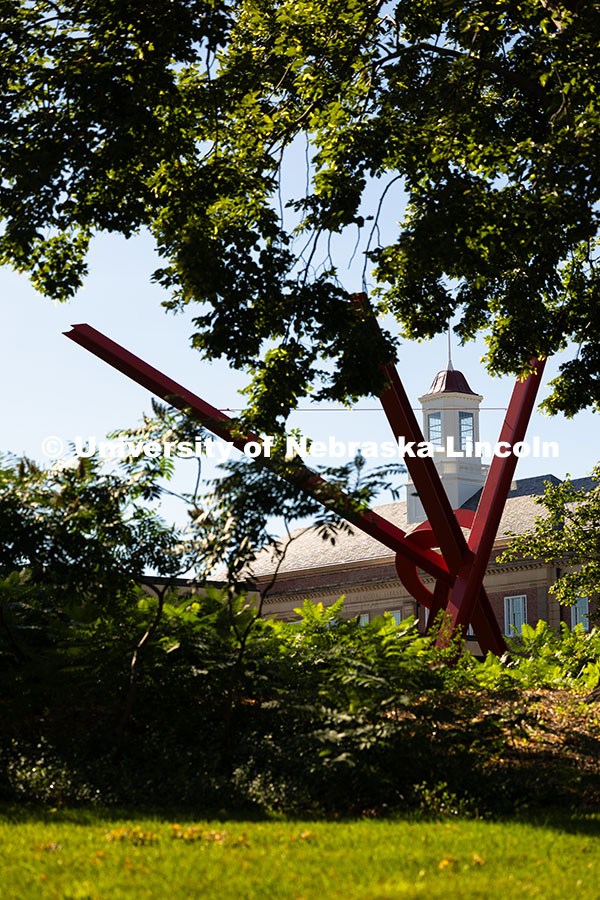 The beams of Old Glory, a sculpture by Mark Di Suvero, frame the cupola of Love Library on a warm, J