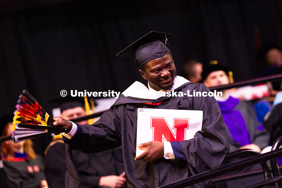 250816_Commencement_3719.jpg Oluseye Fakinlede snaps open a fan after receiving his master's degree from the College of Journalis