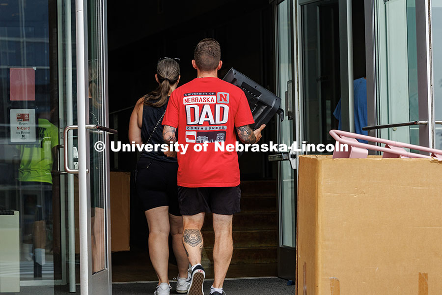 John Bradford carries his son’s TV into Abel Hall sporting a “Nebraska Dad” T-Shirt during day
