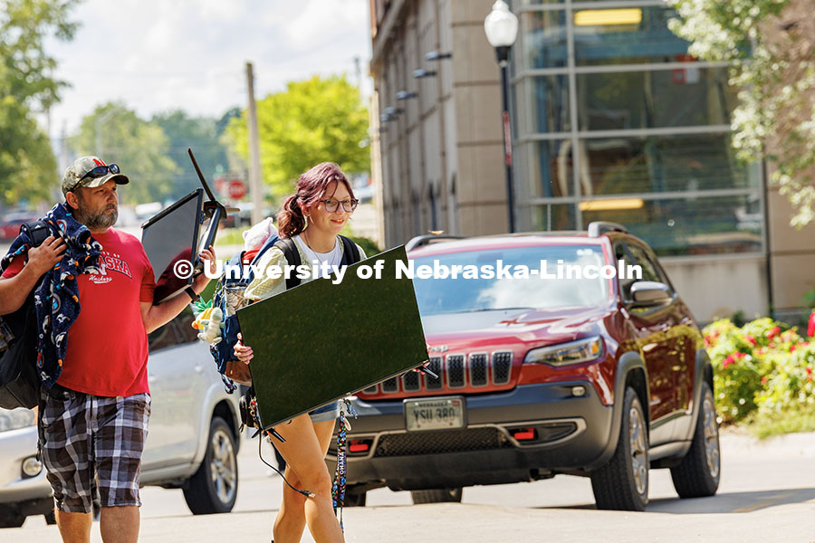 Sophia Bartlett carries a TV into University Suites during move-in day. Residence hall move-in. Augu