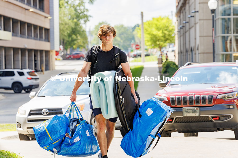 Carsen Davis carries several blue bags into University Suites on move-in day. Residence hall move-in