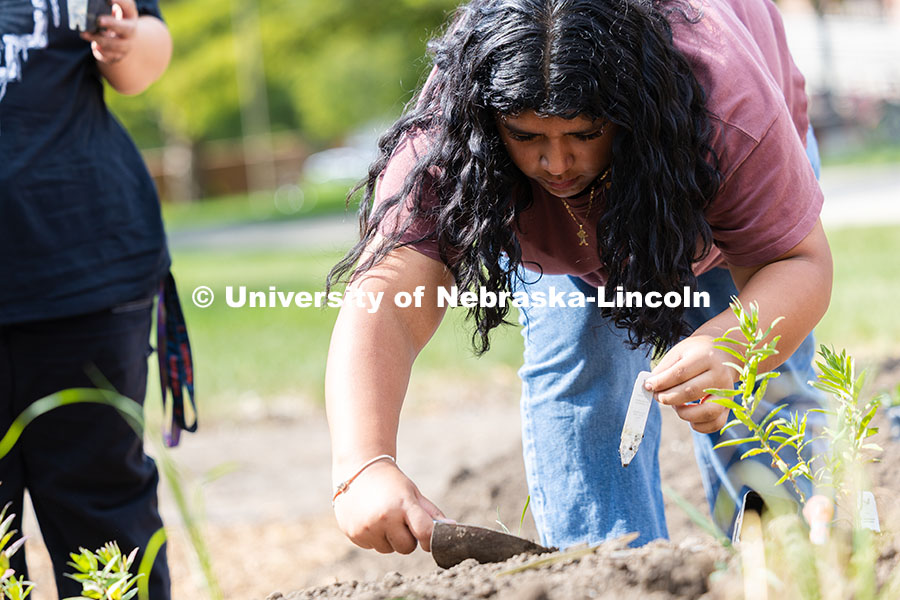 Stephanie Eumana, a first-year student studying psychology, uses a trowel to tamp down dirt while pl