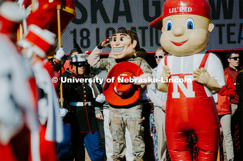 Herbie Husker is decked out in military fatigues and salutes the flag. Lil Red is by his side. Nebra