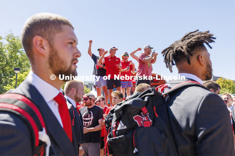 Students stand on the hood of the Bone Yard Bus and cheer as the Huskers walk through the crowd. Stu