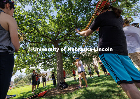 Janelle Johnson of Lincoln leads the trombone section while practicing in the shade of a tree in fro