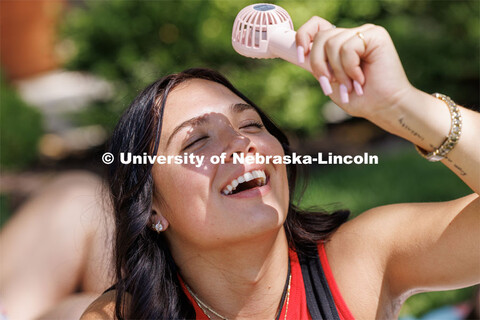 While not a big fan of Thursday’s temperature, Bailey Ostlund of Omaha uses a little fan to create