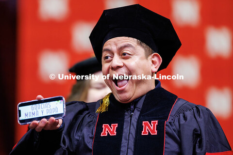 Hector Martinez smiles as he displays the phrase “Gracias Mama y Papa” before being hooded. Grad