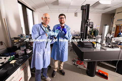 Stephen Morin, Associate Professor of Chemistry, and doctoral student Brennan Watts hold two colorfu
