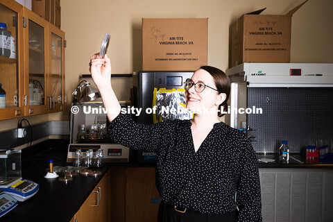 Erin Carr, a postdoctoral research associate, holds up a petri dish filled with streaky, spotty blac