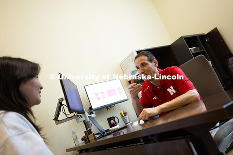 Parker Reed speaks with Mireu Ryu, a senior studying computer science, in his office in Hawks Hall. 