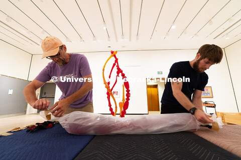 Delan Lonowski (left) and Quentin Fortney (right), on-call exhibition technicians, unwrap part of Ni