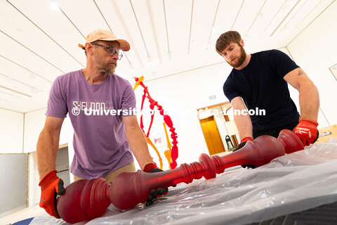 Delan Lonowski (left) and Quentin Fortney (right), on-call exhibition technicians, prepare to lift a