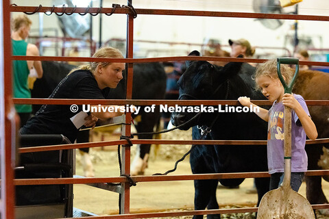 Addy Bates, 17, listens to eight-year-old Sloane Murdoch in the cattle barn at the Otoe County Fair 