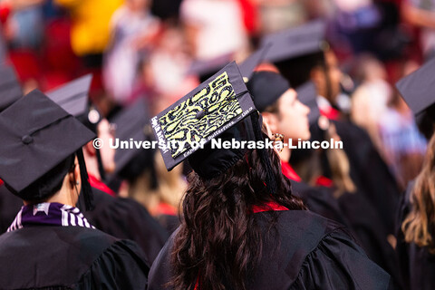 A graduate's cap reads "Enjoy Life. Be Kind. Enjoy the Butterflies." Summer Commencement ceremony in