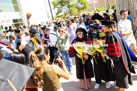 Graduates pose together outside of Pinnacle Bank Arena as other families look for loved ones in the 