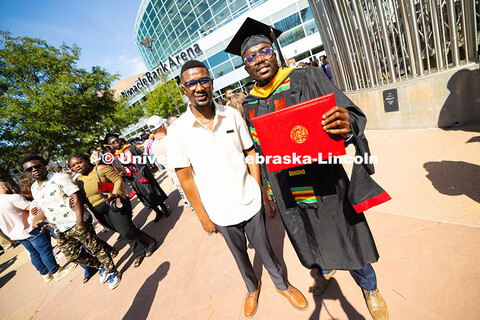 Dela Gohoho holds up his degree outside of Pinnacle Bank Arena. He received his master's in chemical