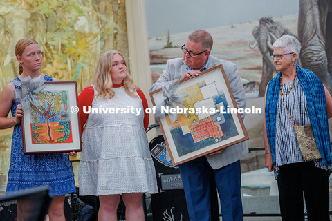 Mike Zeleny and his girls hold up pieces of art given as a farewell gift. Also pictured is the artis
