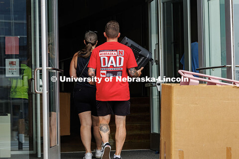 John Bradford carries his son’s TV into Abel Hall sporting a “Nebraska Dad” T-Shirt during day