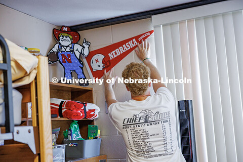 AJ Arensberg, a Sports Media and Communication major, puts up a Nebraska flag in his dorm in Abel Ha