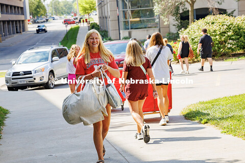 Alaina Hadford smiles as she carries her items into University Suites during move-in day. Residence 