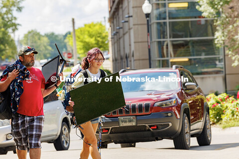 Sophia Bartlett carries a TV into University Suites during move-in day. Residence hall move-in. Augu