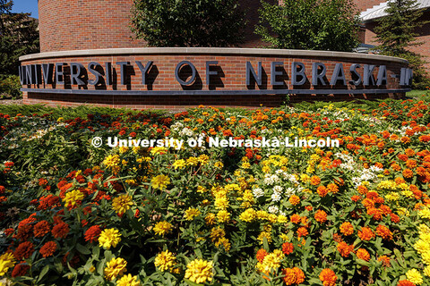 An array of flowers grow in-front of a University of Nebraska-Lincoln sign outside of the Van Brunt 