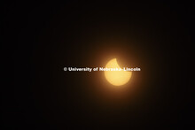 By 12:04 pm, the sun was almost half covered. Students gather on the green space between the Nebrask
