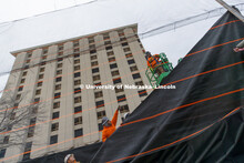Worker with Ark Wrecking hang fabric over a mesh wall erected along 17th street in Lincoln. The wall