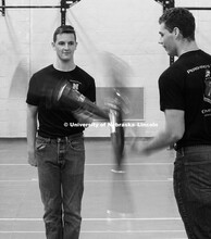 Air Force Cadet 3rd Class Zachary Day and Army Cadet Private Tyler Mona work on twirling their rifle