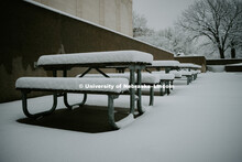 The walkways and picnic benches are covered in snow between the Sheldon Art Gallery and Pound Hall o
