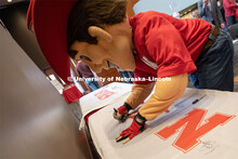 Herbie signs one of the four Alumni N150 flags. The flags will travel around the world to various al