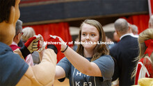 Kelsey Schlichtman fist bumps Herbie Husker as she runs through a tunnel walk of high-fives at the F