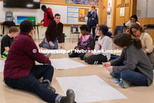 Luke Novack middle explains activities as students and Grace Stallworth left listen. A new research 