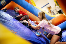 Emma Vertin helps a youngster make it up a climbing ramp in an inflatable maze. She and others from 