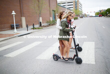 Four students roll onto campus riding electric scooters. April 22, 2019. 