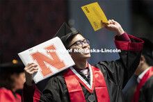Jinhoong Cheng gestures to family and friends after receiving his College of Business diploma. Under