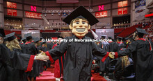 Herbie Husker, decked out in a cap and gown, leads the procession off stage Saturday morning. Underg