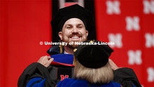 Zachary Myers is hooded by his advisor Sue Swearer. 2019 Summer Commencement at Pinnacle Bank Arena.