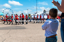 Kids watch the Cornhusker Marching Band march by. The University of Nebraska represents and celebrat