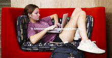 Emily Diesing, a freshman from Omaha, curls up in a chair in Love Library while participating in an 