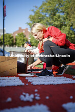 Amanda Fuechtmann, freshman from Minnesota, glues poms to a plywood display outside the Theta Xi hou